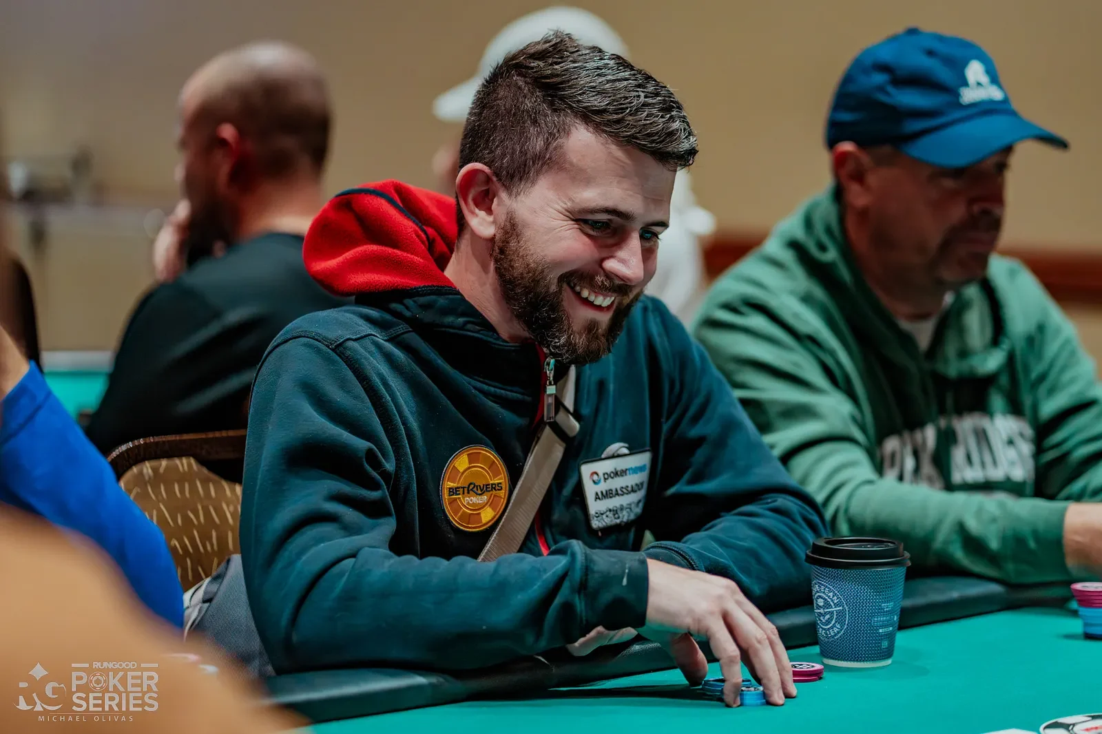 Keith Becker playing poker at a live event wearing BetRivers and PokerNews ambassador patches
